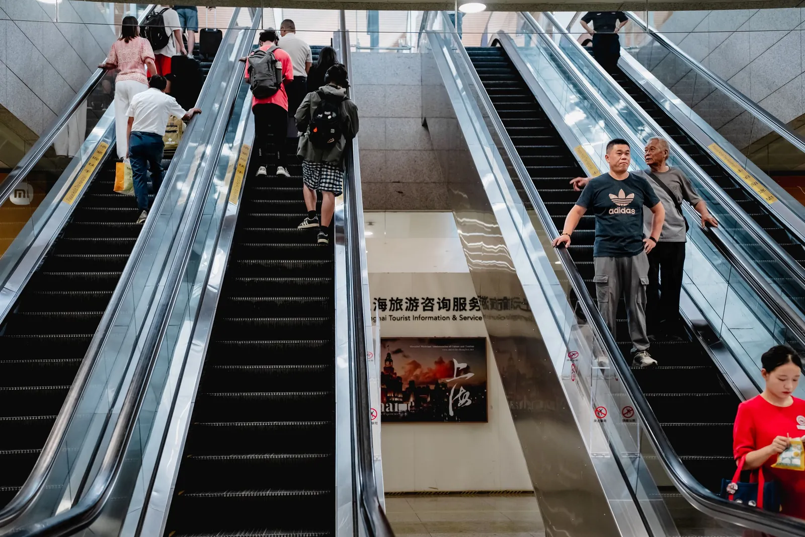 Passengers riding the escalators inside a busy Shanghai metro station.