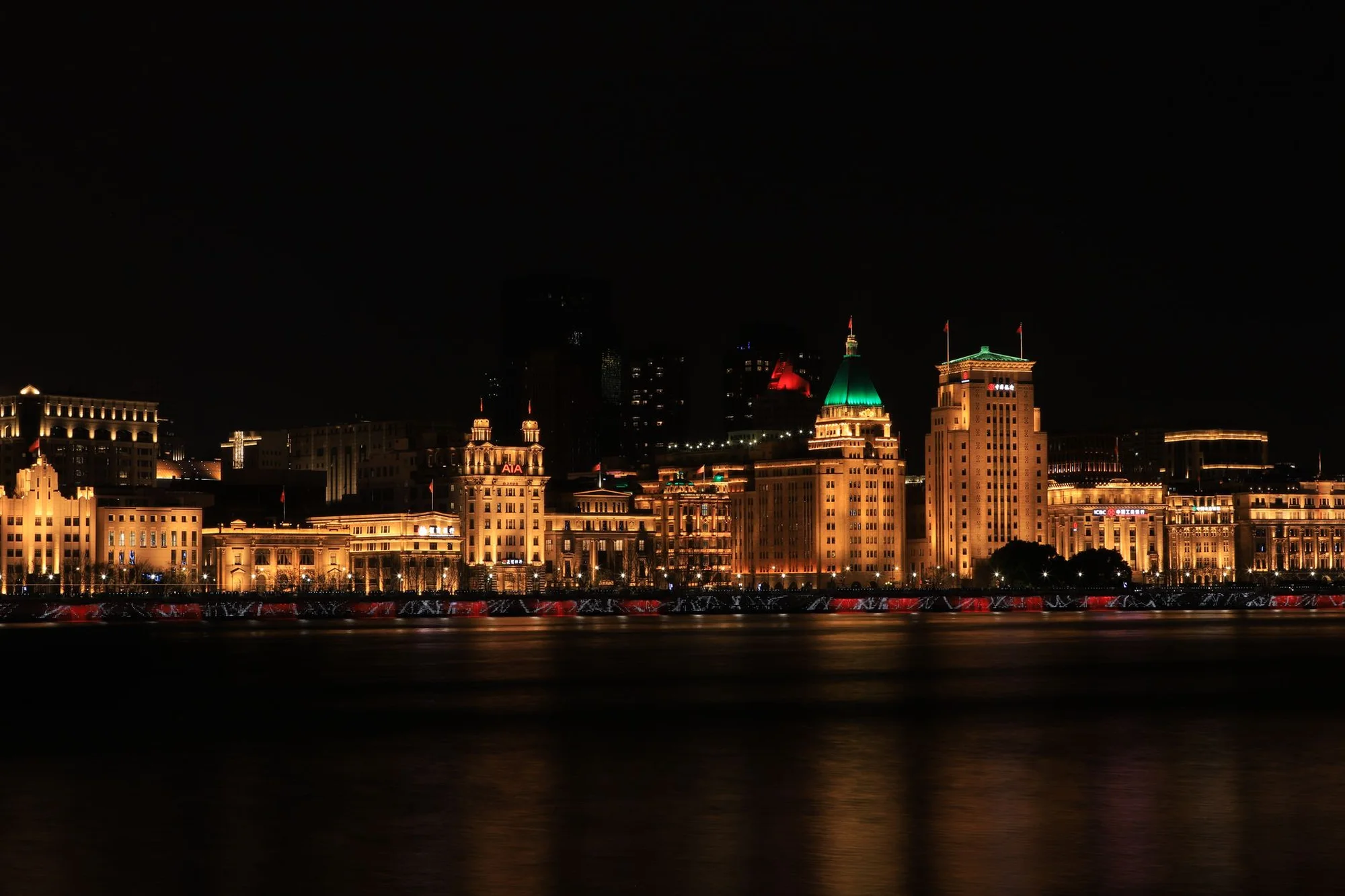 The Shanghai skyline along the Bund at dusk with the river in the foreground