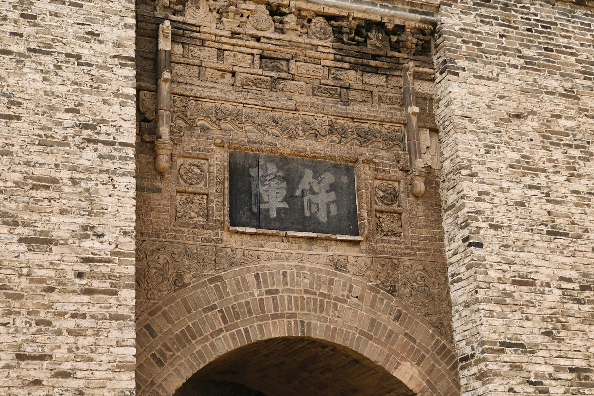A historic Chinese city gate with carved stonework and an arched passageway