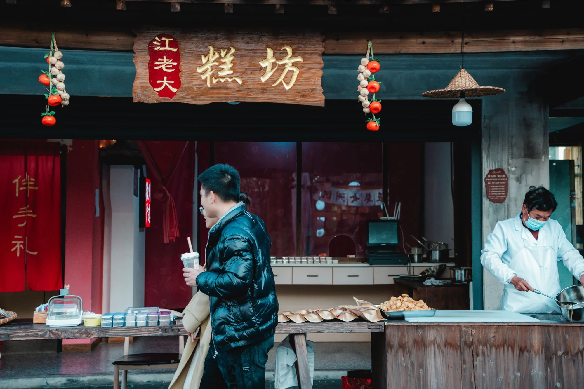 A Chinese street food stall with Chinese signage and a customer holding a cup