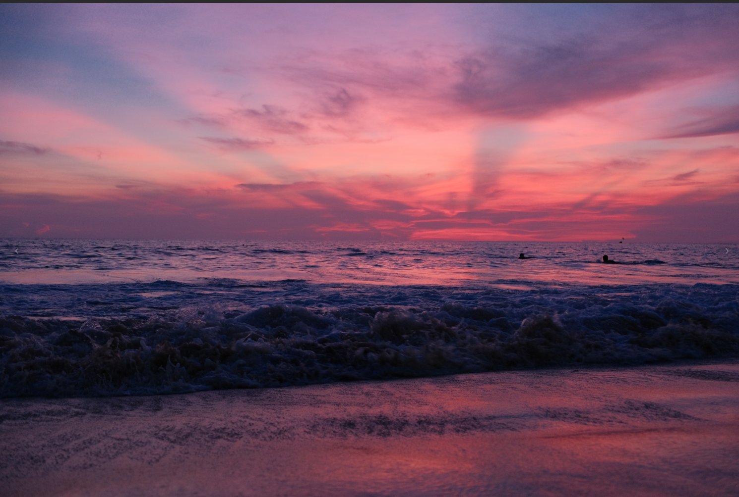 Pastel pink and purple dusk over a beach with breaking waves and a swimmer silhouette in the surf