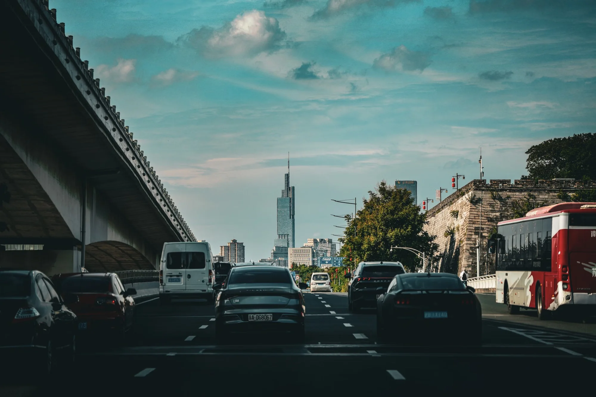 Cars on a multi-lane road in a Chinese city, with local license plates visible under an overpass