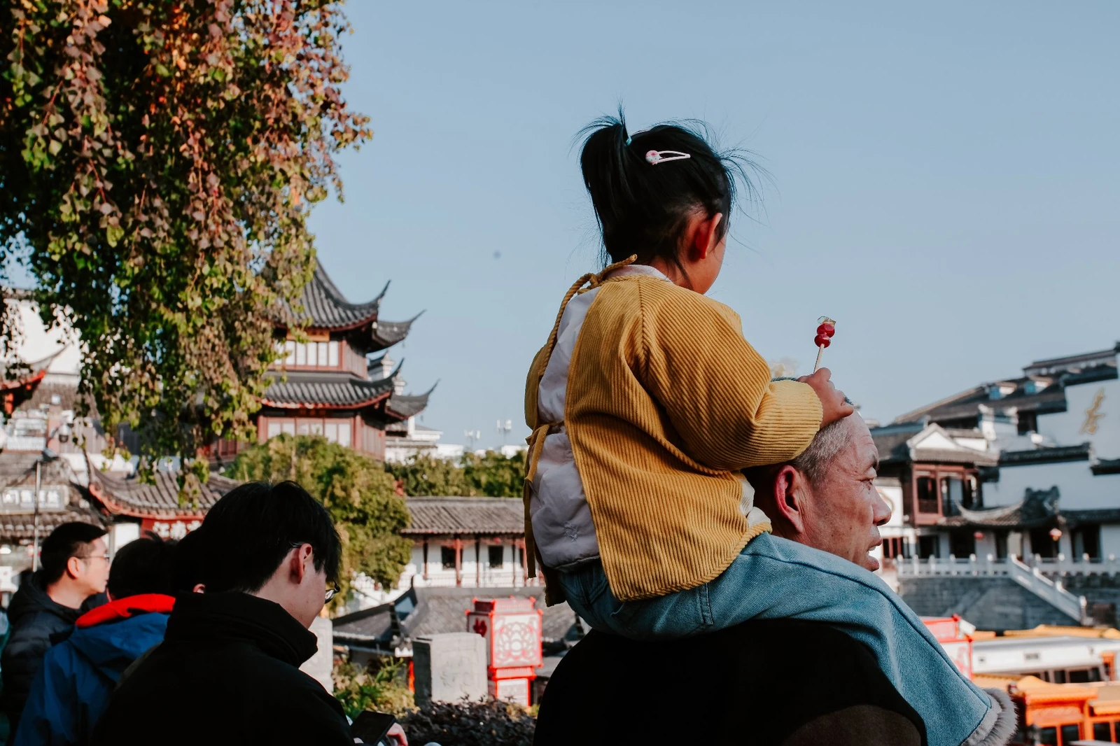 A child on an adult's shoulders at a Chinese temple complex