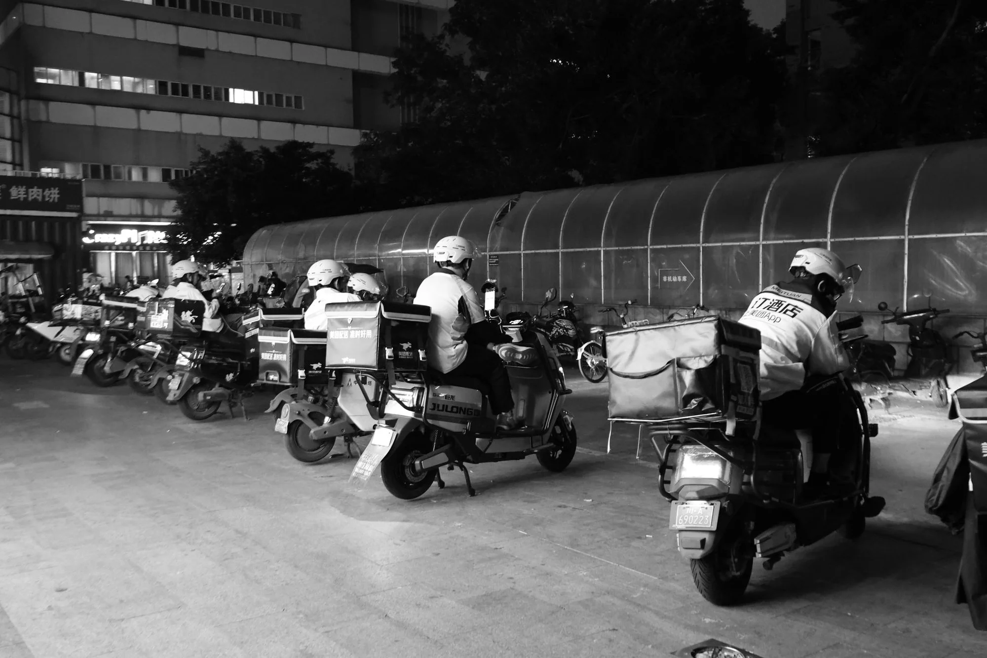 A food delivery rider on an electric scooter carrying an insulated bag through a Chinese city street