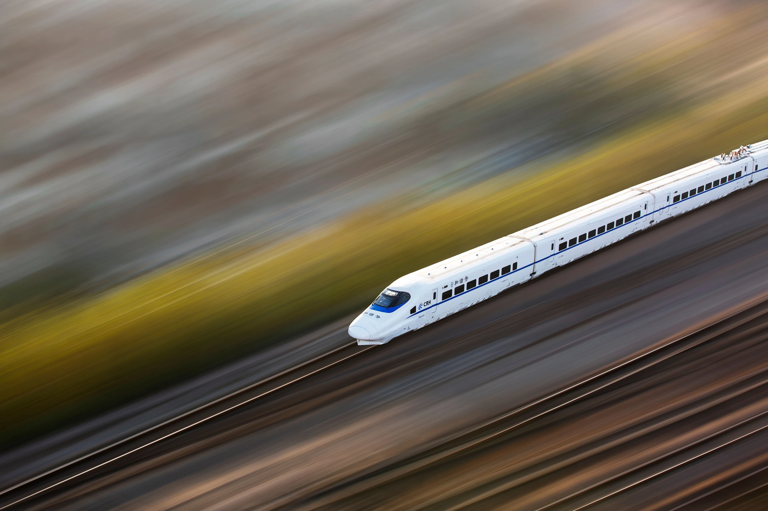 A CRH high-speed train speeds through the Chinese countryside with a motion blur of autumn fields