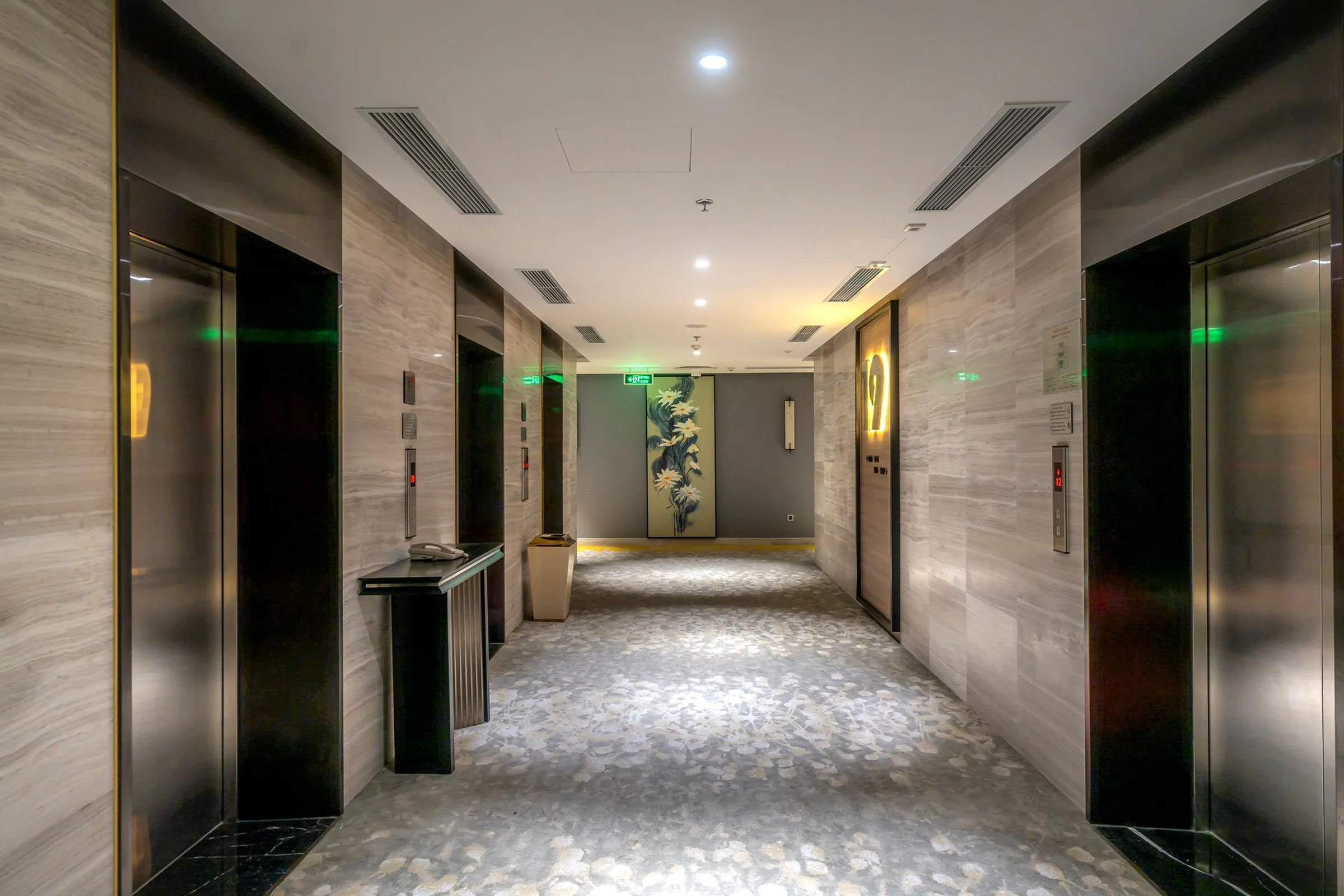 A modern Chinese hotel corridor with elevators and Chinese-language exit signs