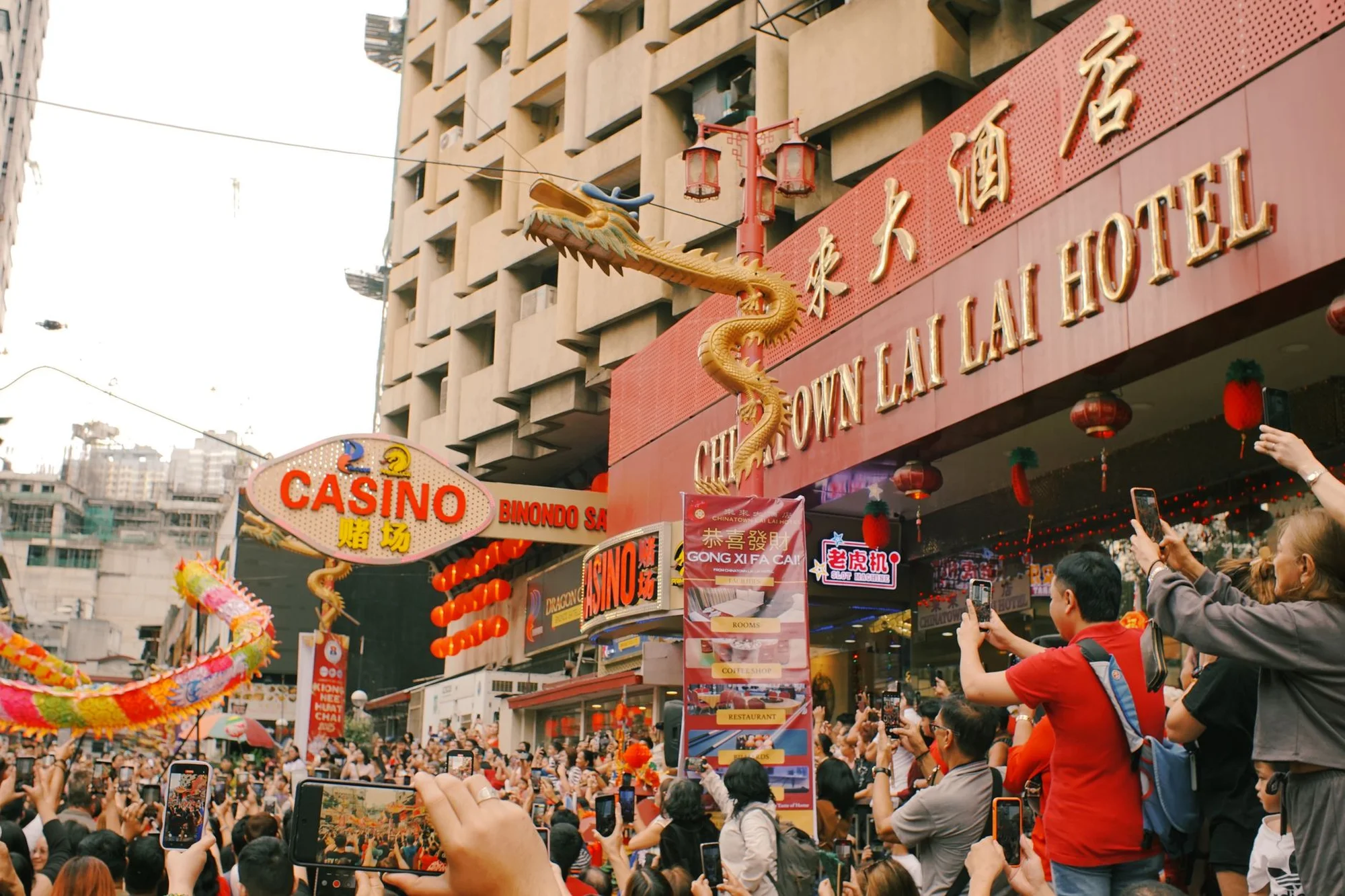 A busy Chinese city street scene with people using smartphones and red lanterns overhead