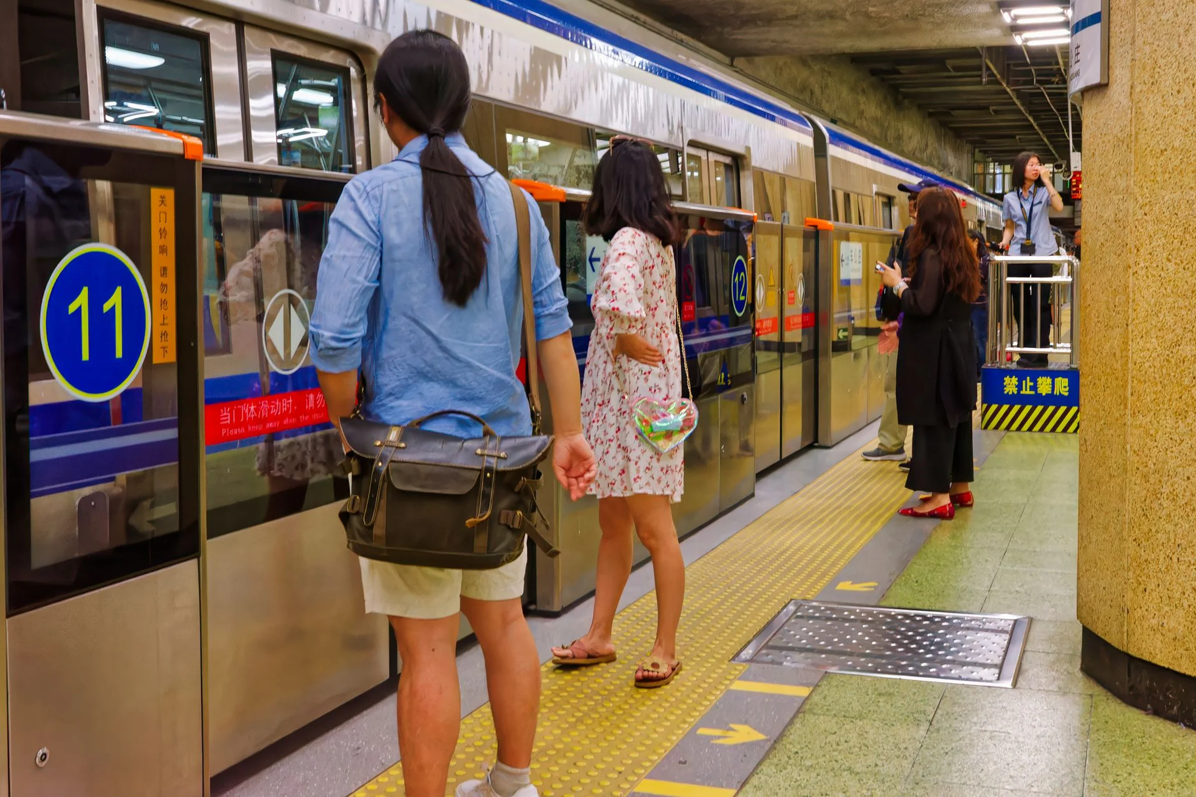 Commuters waiting on a Beijing subway platform behind the platform screen doors