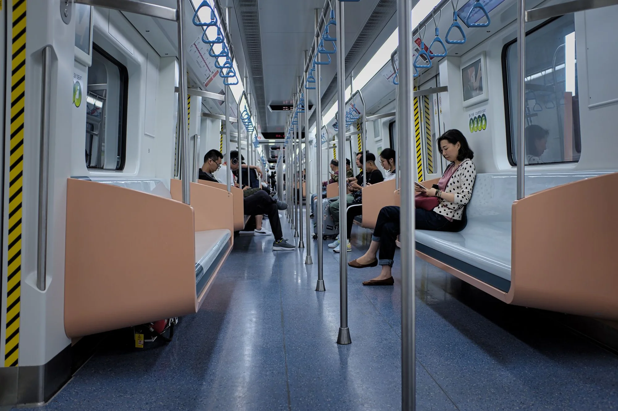 Passengers seated and standing inside a Chinese subway carriage, some looking at phones