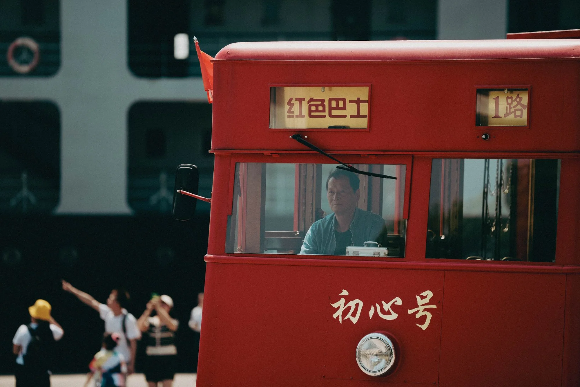 A red Chinese city bus with the route number 1 displayed and a driver visible behind the windscreen