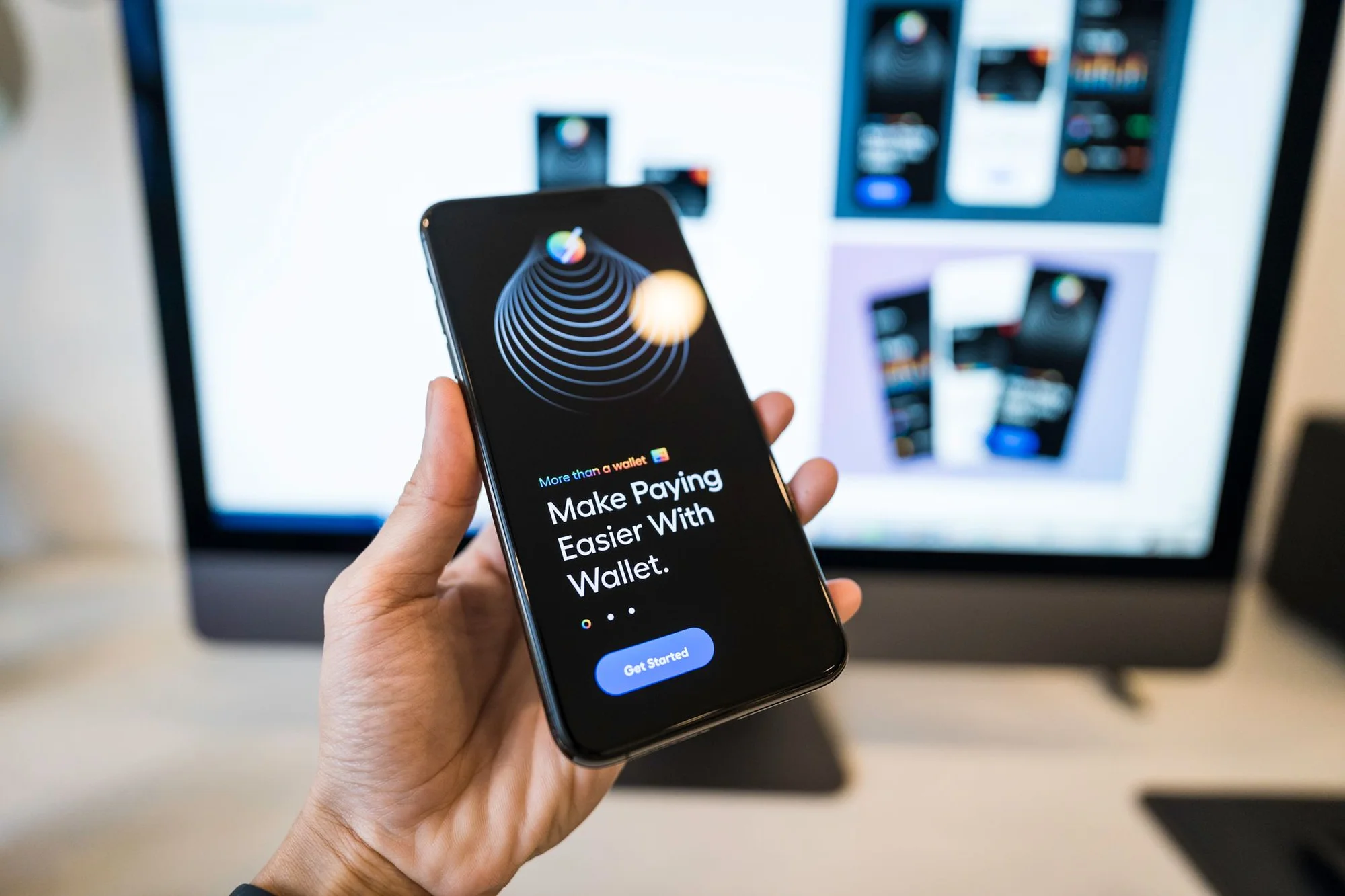 A hand holding a phone showing a mobile wallet app getting started screen