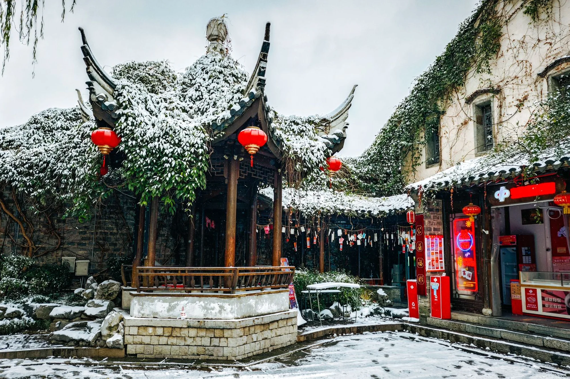 A traditional Chinese courtyard covered in snow with red lanterns