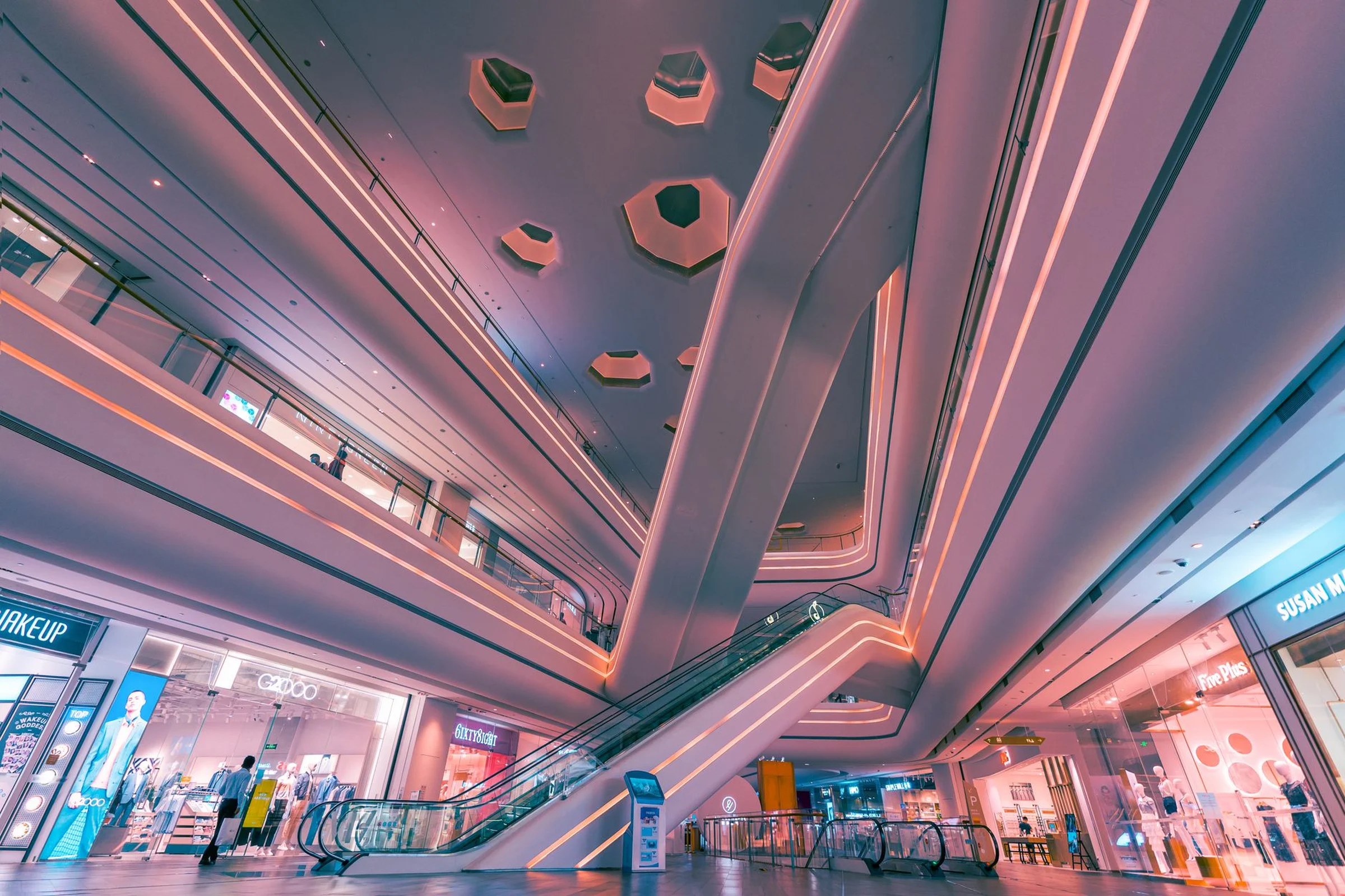 A modern Chinese shopping mall interior with escalators and lit storefronts, no people close-up