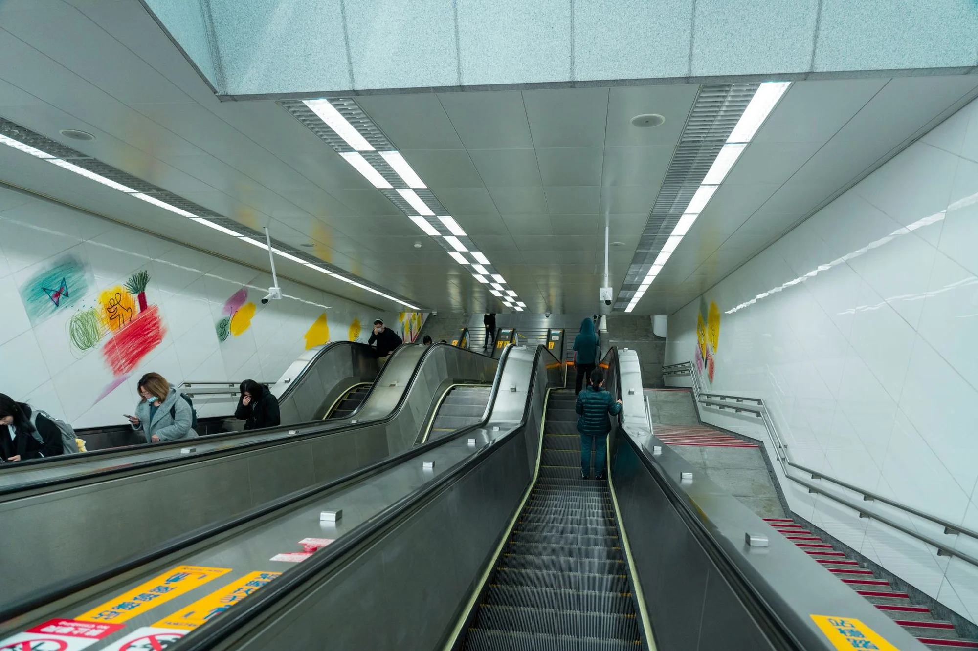 A modern Chinese metro station with escalators and Chinese signs on the wall