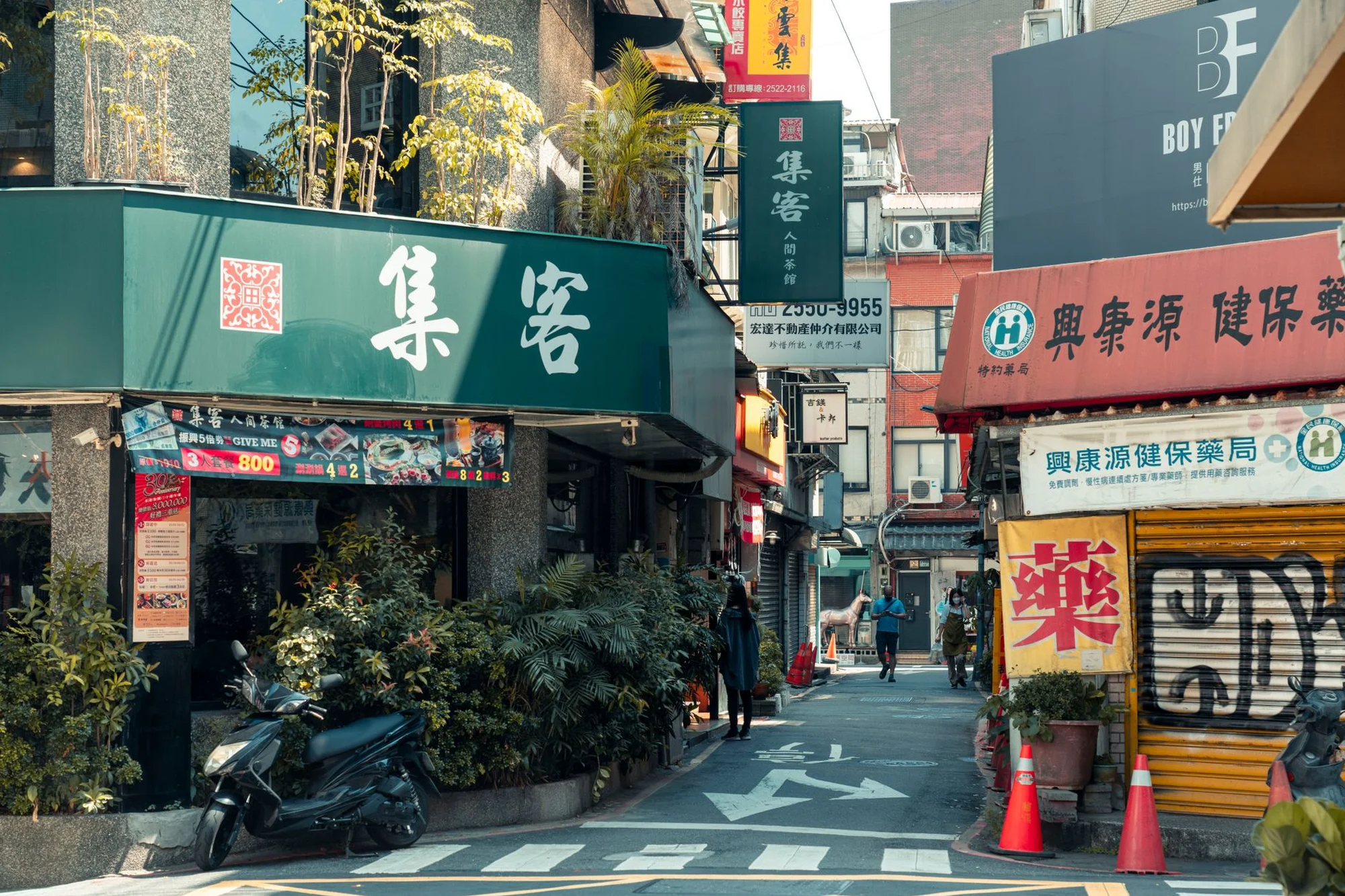 A Chinese shopping street with hanging shop signs and parked scooters