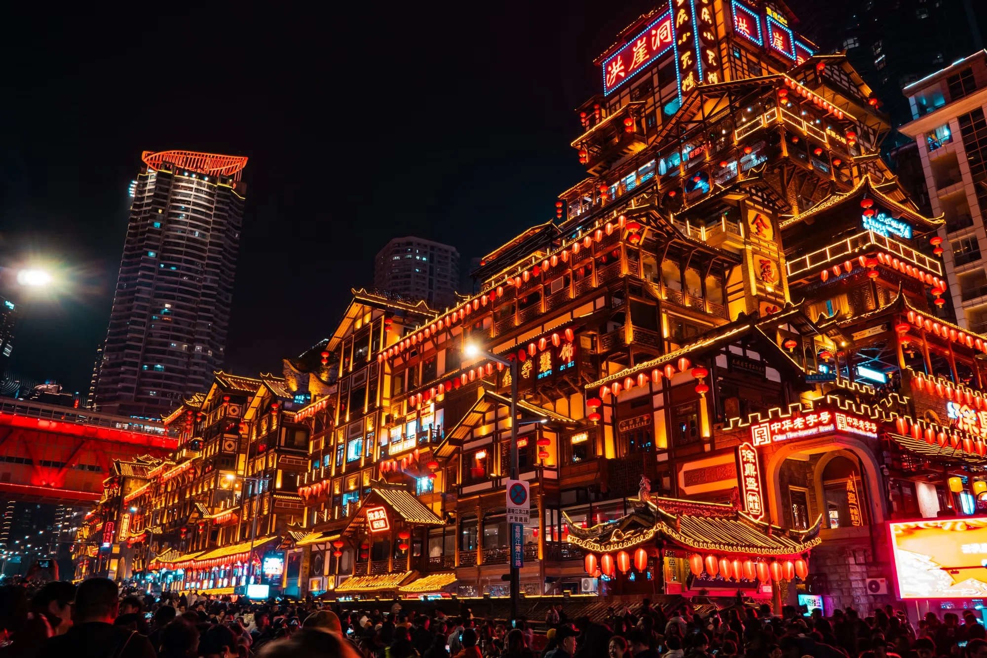 A well-lit, lively bar street in a Chinese city at night with people walking openly