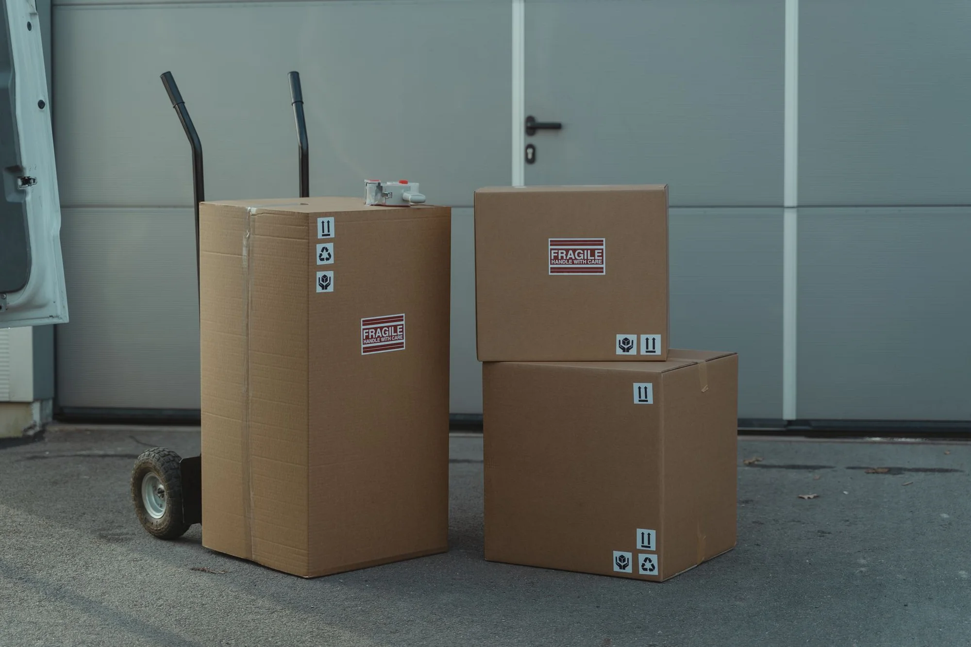 Cardboard parcels on a hand truck outside a delivery vehicle