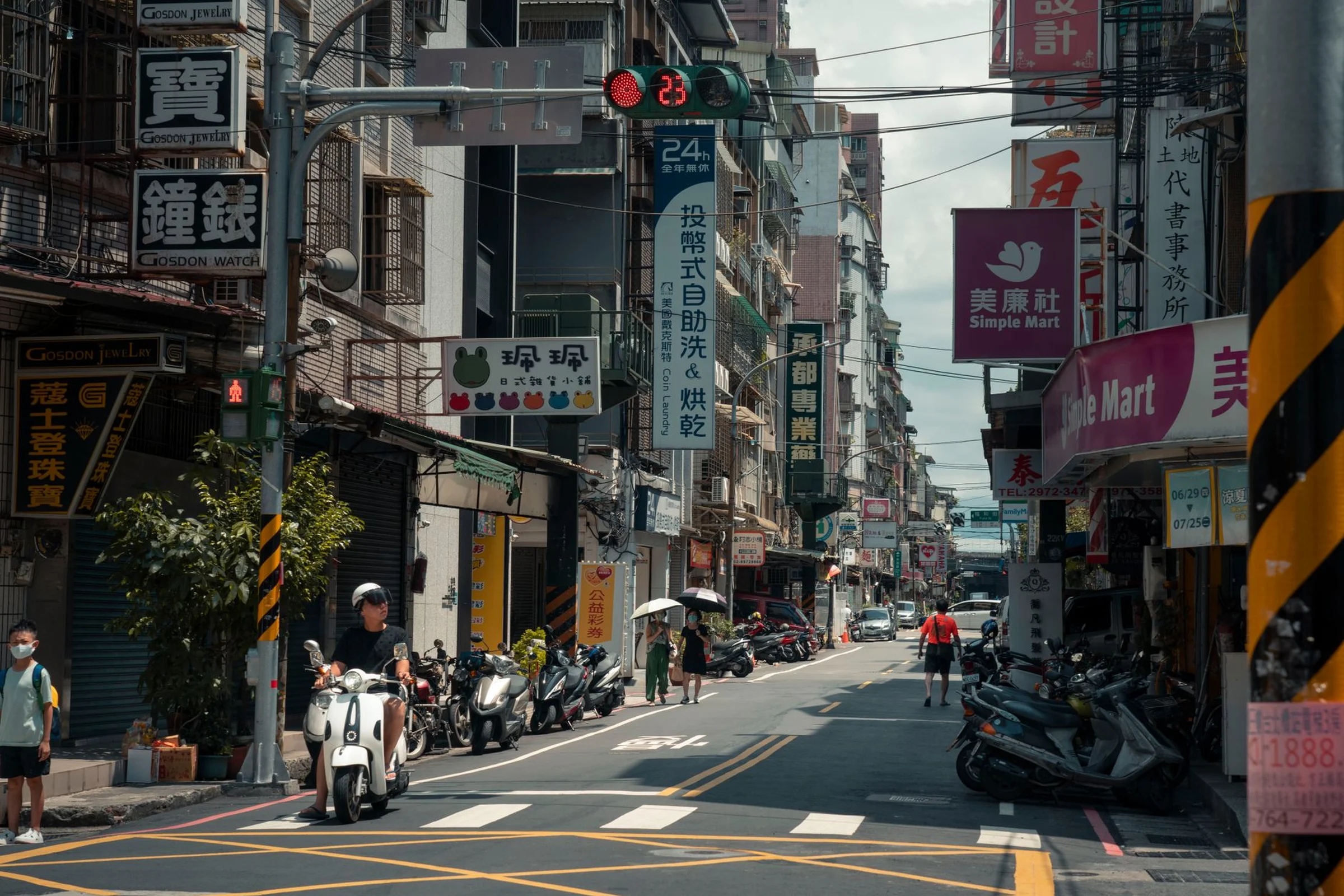 A Chinese shopping street with hanging shop signs, parked scooters and Chinese characters on storefronts