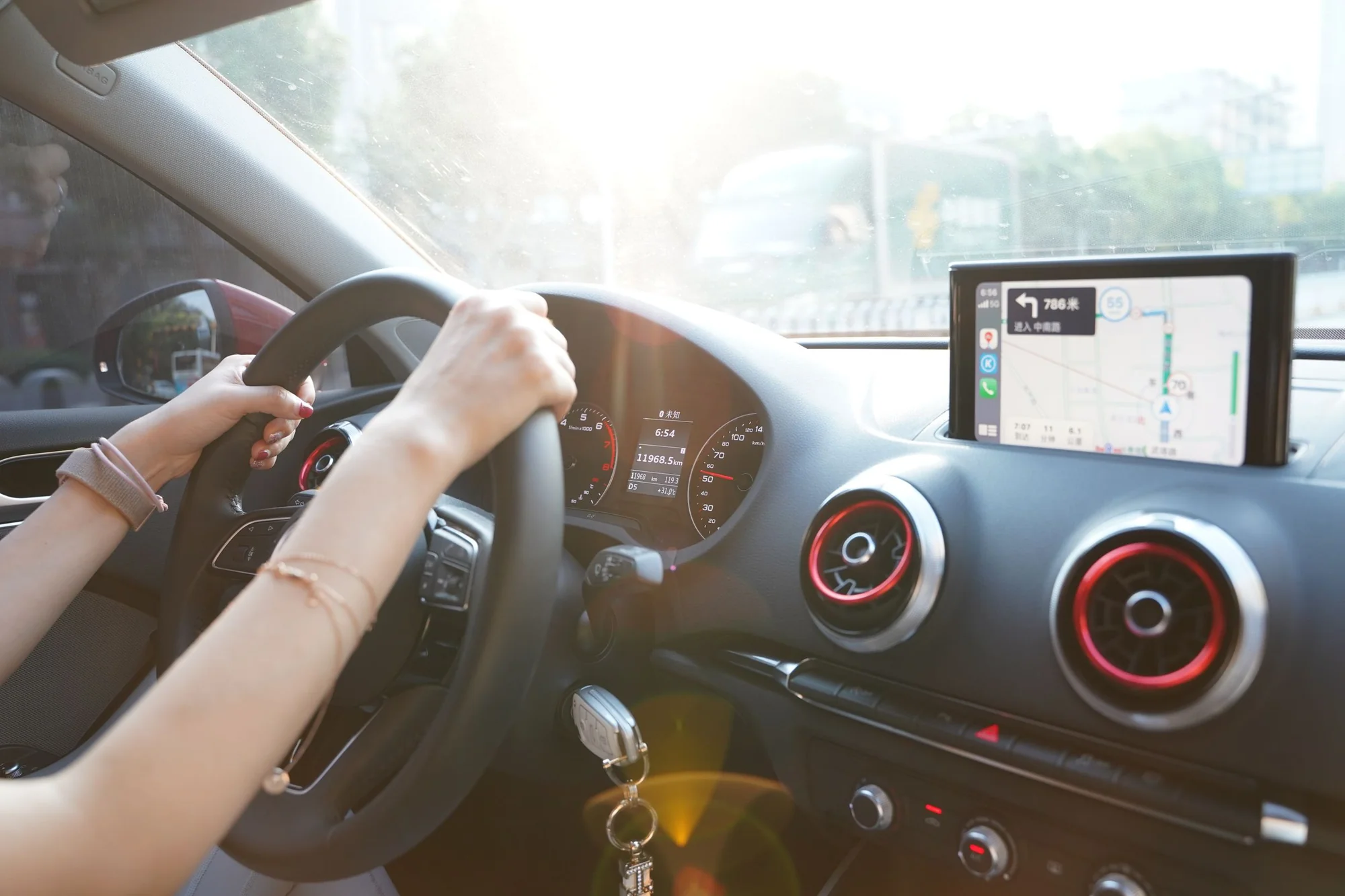 A driver in China holding the wheel, with a Chinese-language navigation screen, driving on a temporary driving permit
