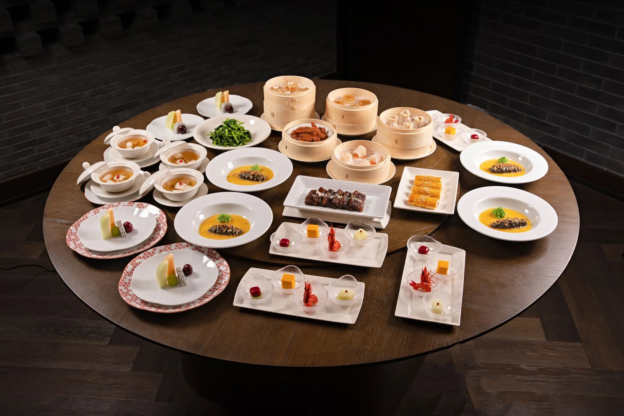 A round table in a Chinese restaurant covered with dim sum dishes in bamboo steamers and on plates