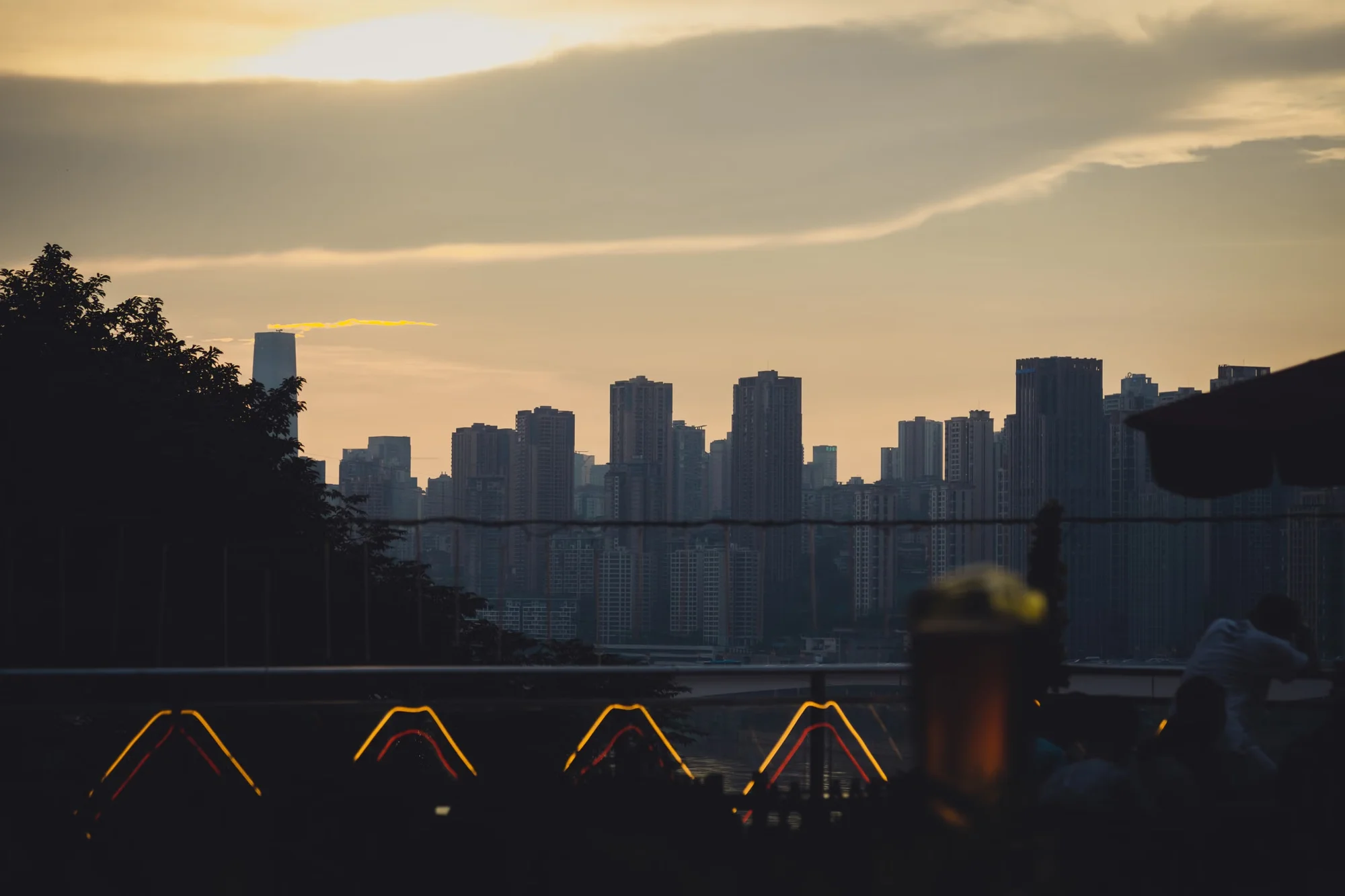 A first-time visitor holding a China guidebook and phone with maps open, looking at a modern Chinese city skyline at dusk