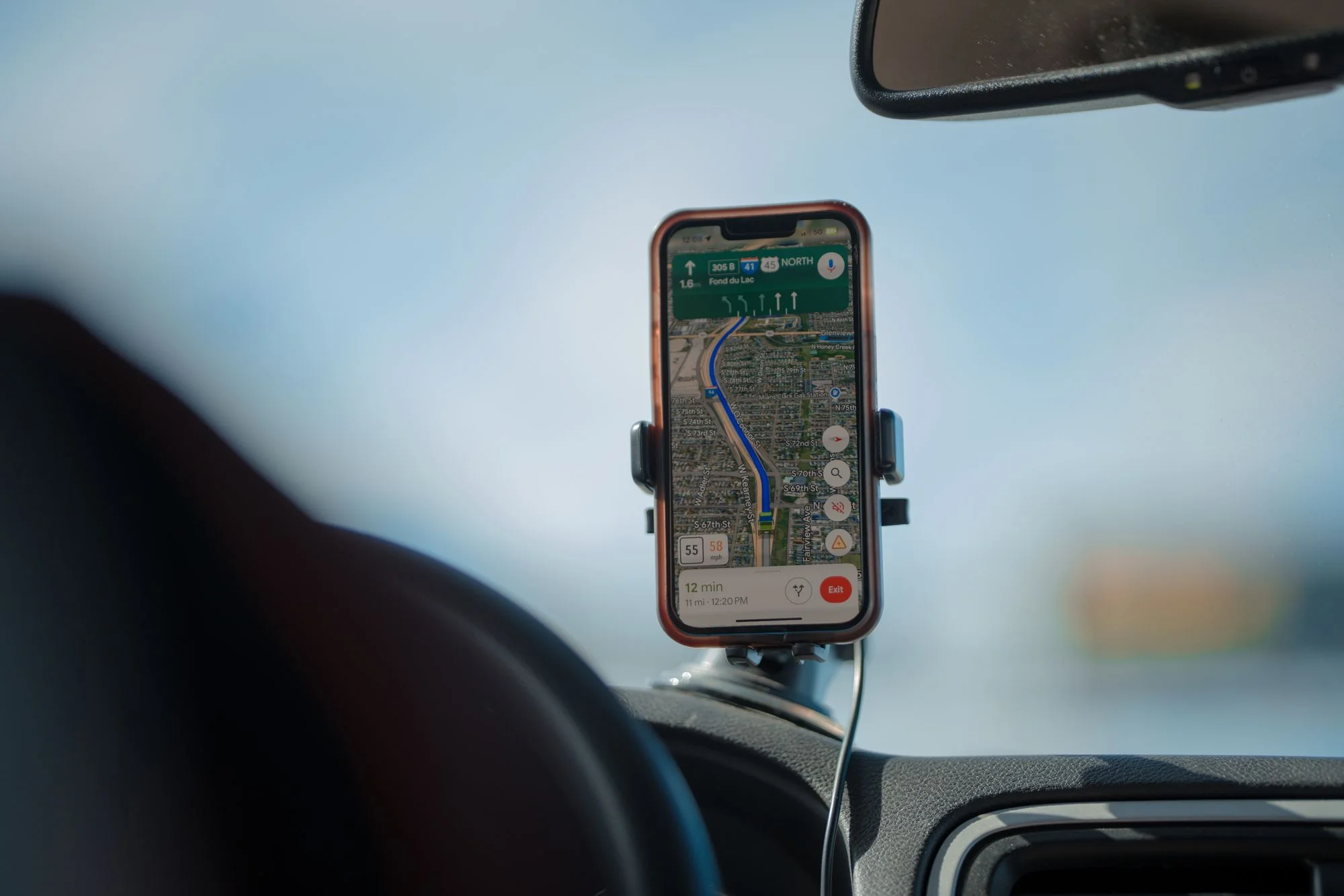 A smartphone showing a navigation app map on a car dashboard