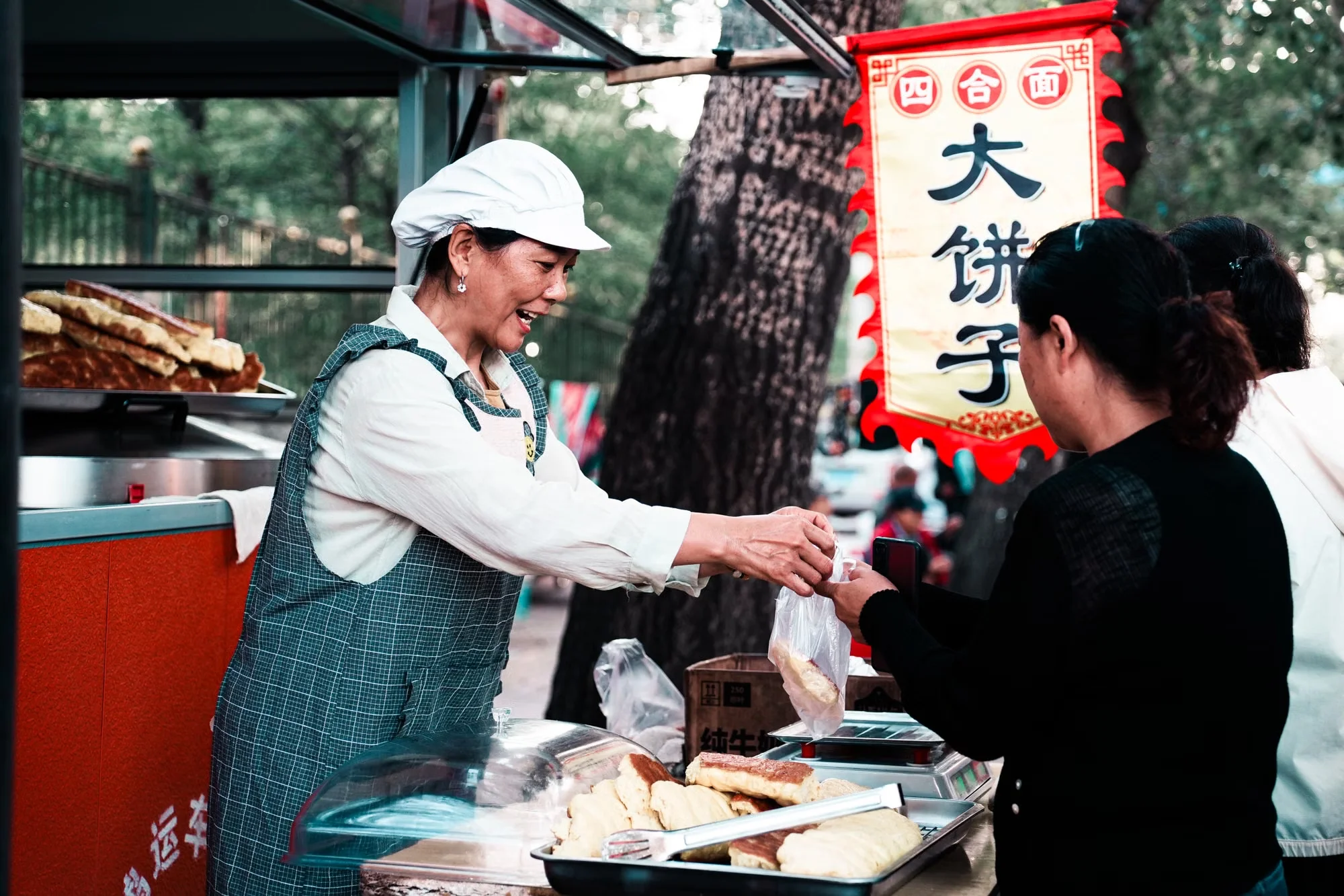 A street vendor serving food at a small stall in China, the kind of shop where phone payments are common