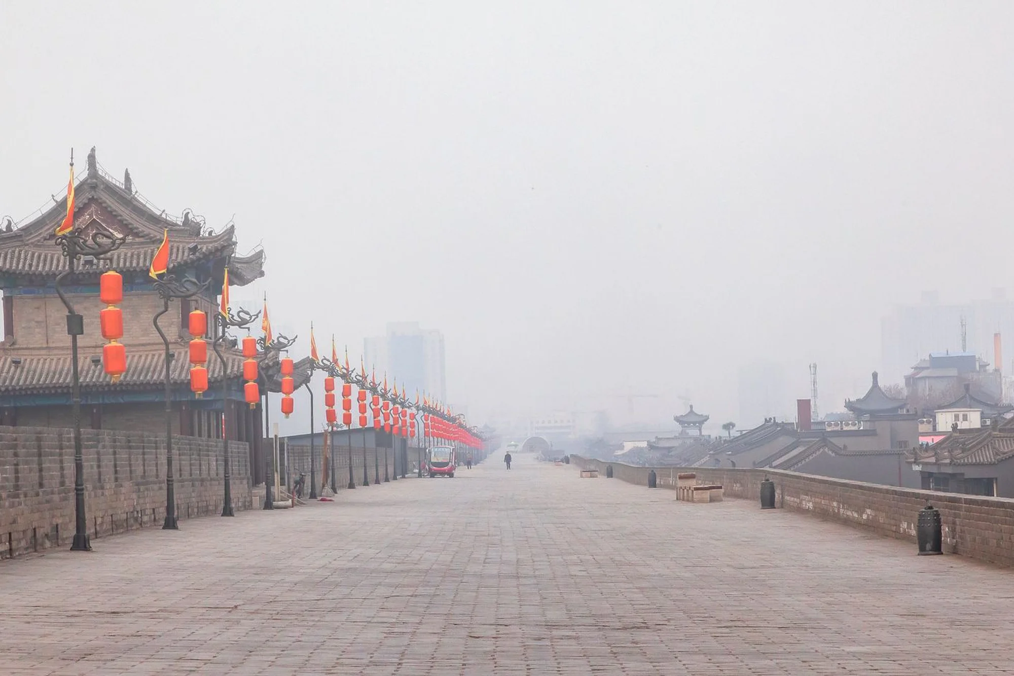 The ancient City Wall of Xi'an with red lanterns and traditional gate towers on a misty day