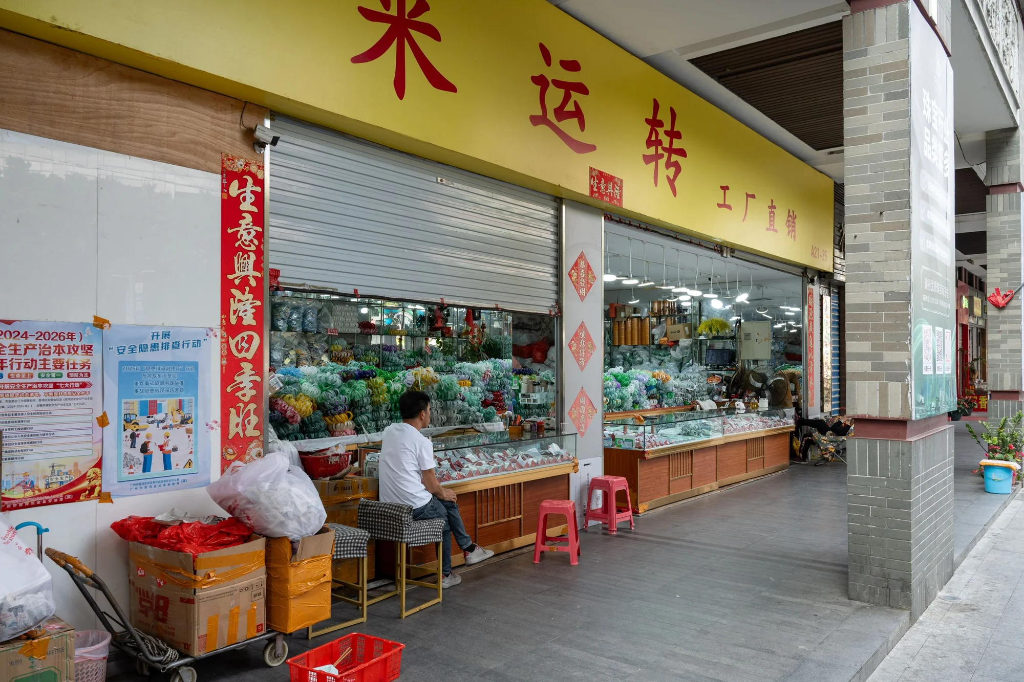 A crowded street market in China with stalls, shoppers and hanging goods