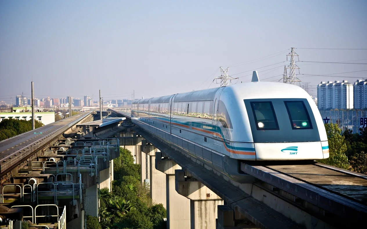 Shanghai Maglev train crossing an elevated viaduct with the city's skyline in the background, near Longyang Road.
