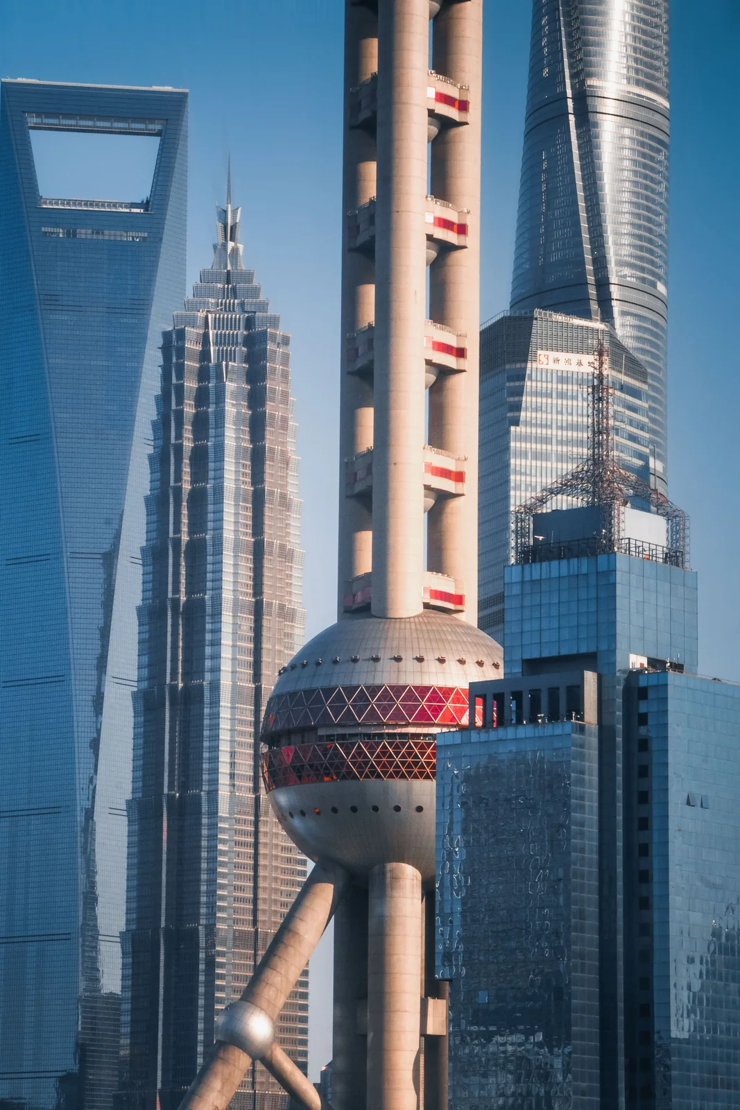 The Lujiazui skyline at golden hour in Pudong, Shanghai: the Oriental Pearl Tower in front and the Shanghai Tower, Shanghai World Financial Center and the bottle-opener behind, with IFC and other towers in the background.