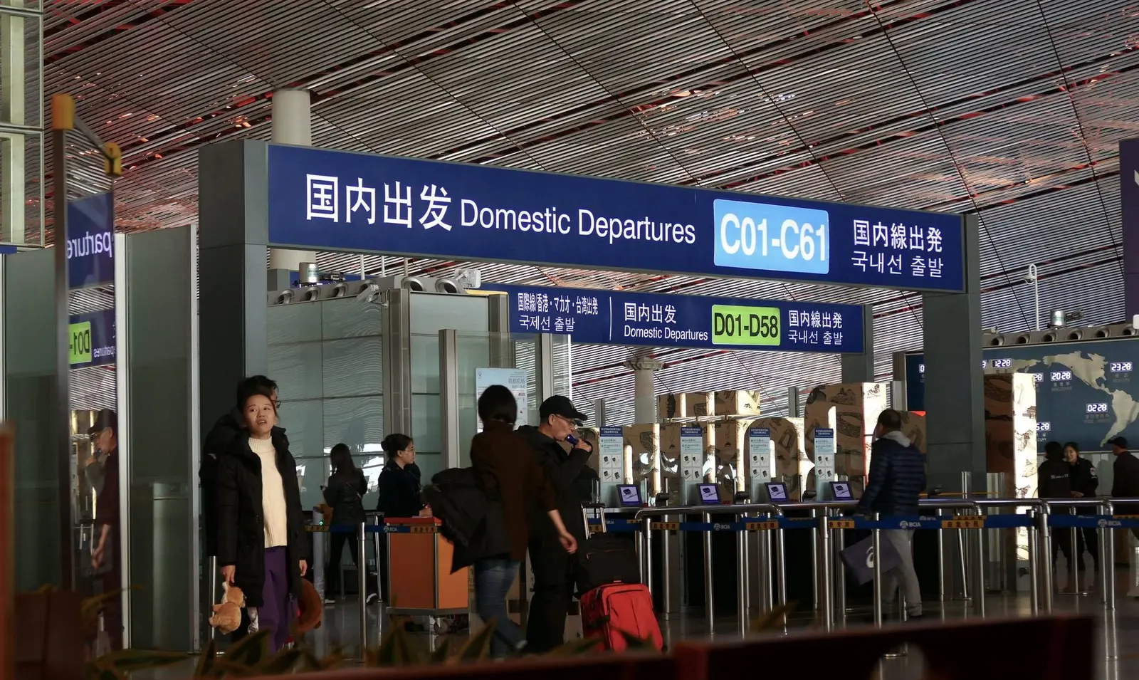 Travelers walk through a modern Chinese airport terminal with bilingual departure signage and gate queues